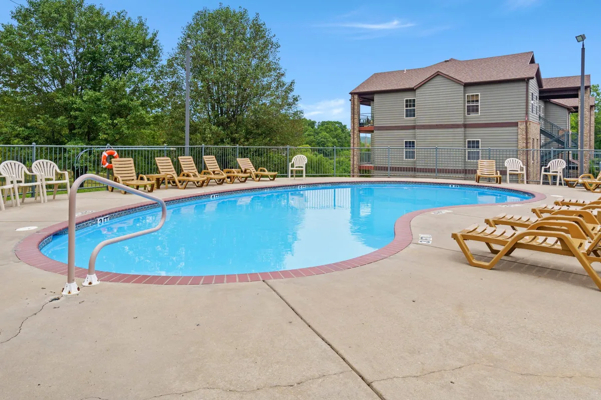 This image shows an inviting swimming pool area with lounge chairs surrounded by lush greenery. The atmosphere is leisurely, perfect for sunbathing, swimming, or simply relaxing by the pool, which ties in with premium resort amenities.