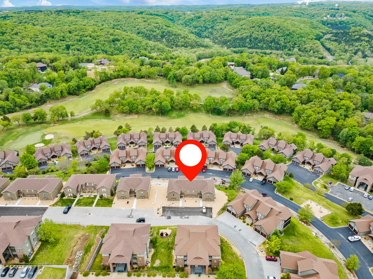 This peaceful exterior shot provides an elevated view of the neighborhood with the golf course winding through rolling hills and lush greenery. The image captures the tranquil community atmosphere, with sunset hues in the background suggesting the potential for relaxing evenings after a day of play.