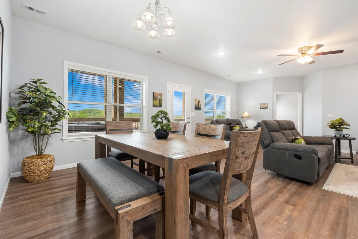 The image showcases an inviting and beautifully decorated open-concept living and dining area. A stylish dining table is perfectly set for gatherings, while a cozy sofa sits nearby, surrounded by vibrant potted plants and tasteful artwork. The space is filled with warm natural light, creating a welcoming atmosphere for families or groups to relax, dine, and make memories together.
