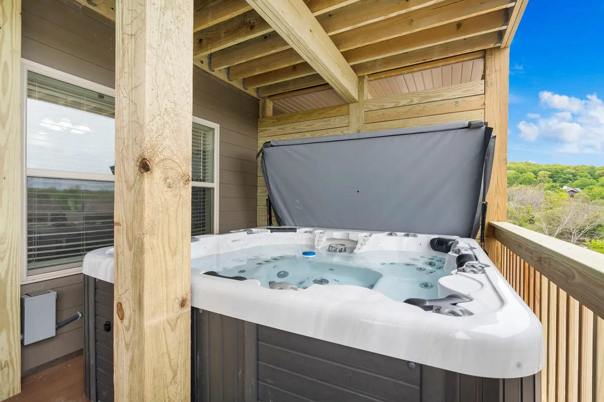 A cozy balcony with a hot tub framed by rustic wooden beams, offering a breathtaking view of the surrounding natural landscape. The image captures the essence of a secluded outdoor escape, with room for guests to relax and enjoy the scenery.