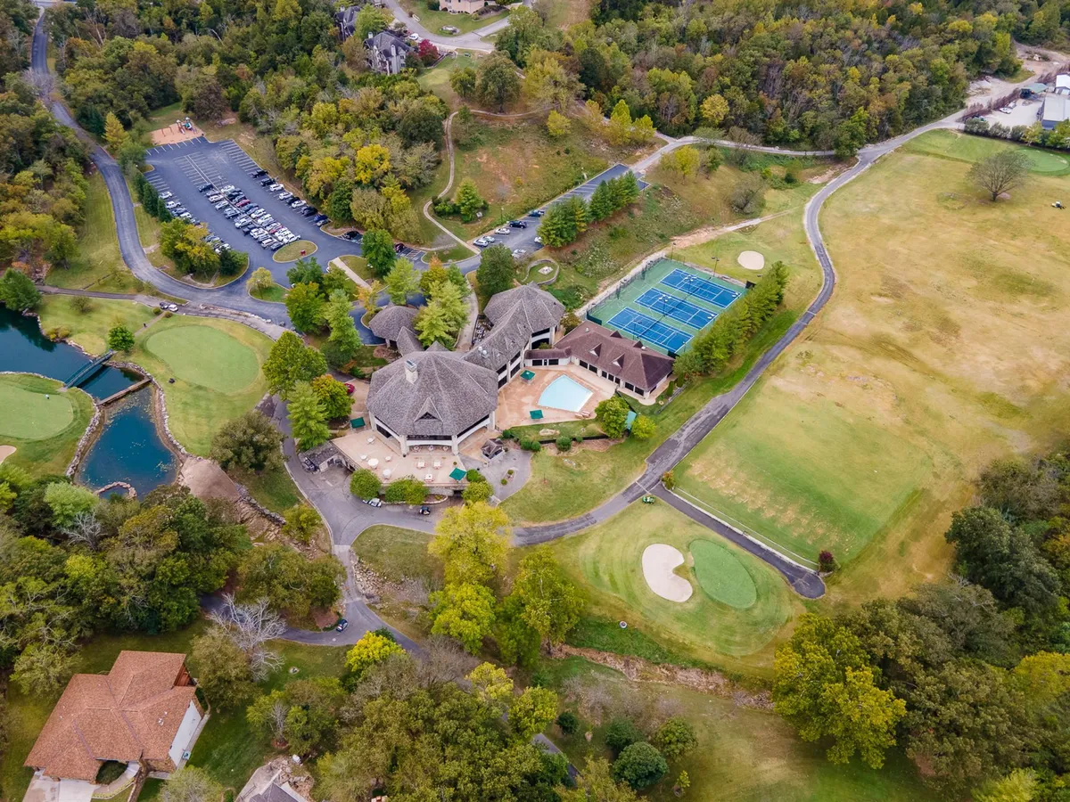 This exterior image features a vibrant view of the Stonebridge community's clubhouse, golf course, swimming pool, and tennis courts. The clubhouse stands as a social hub, with the green fairways and the sparkling pool visible, all surrounded by lush landscaping.