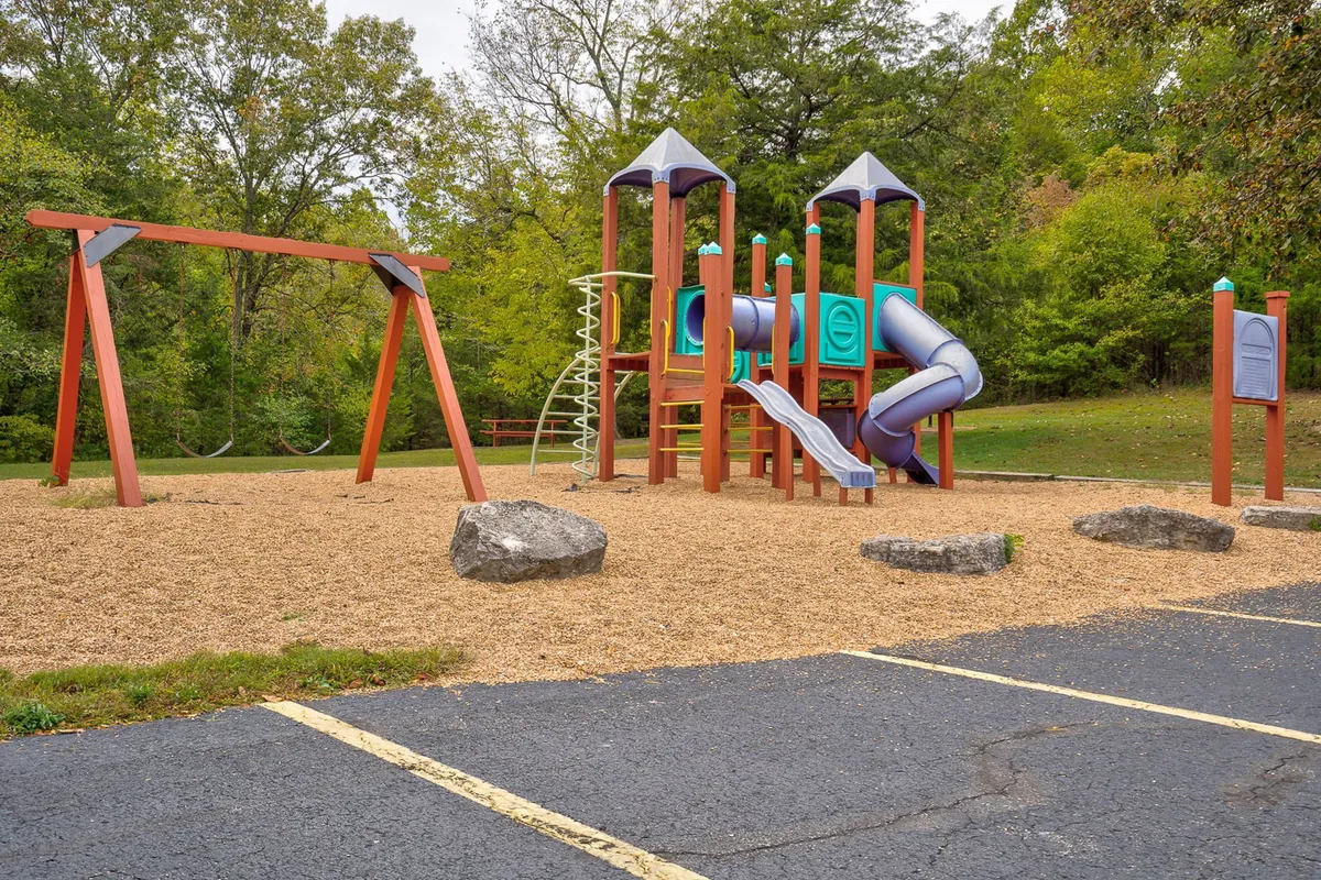 A colorful playground set with swings and climbing frames is surrounded by soft grass, inviting children and families to play and socialize outdoors.